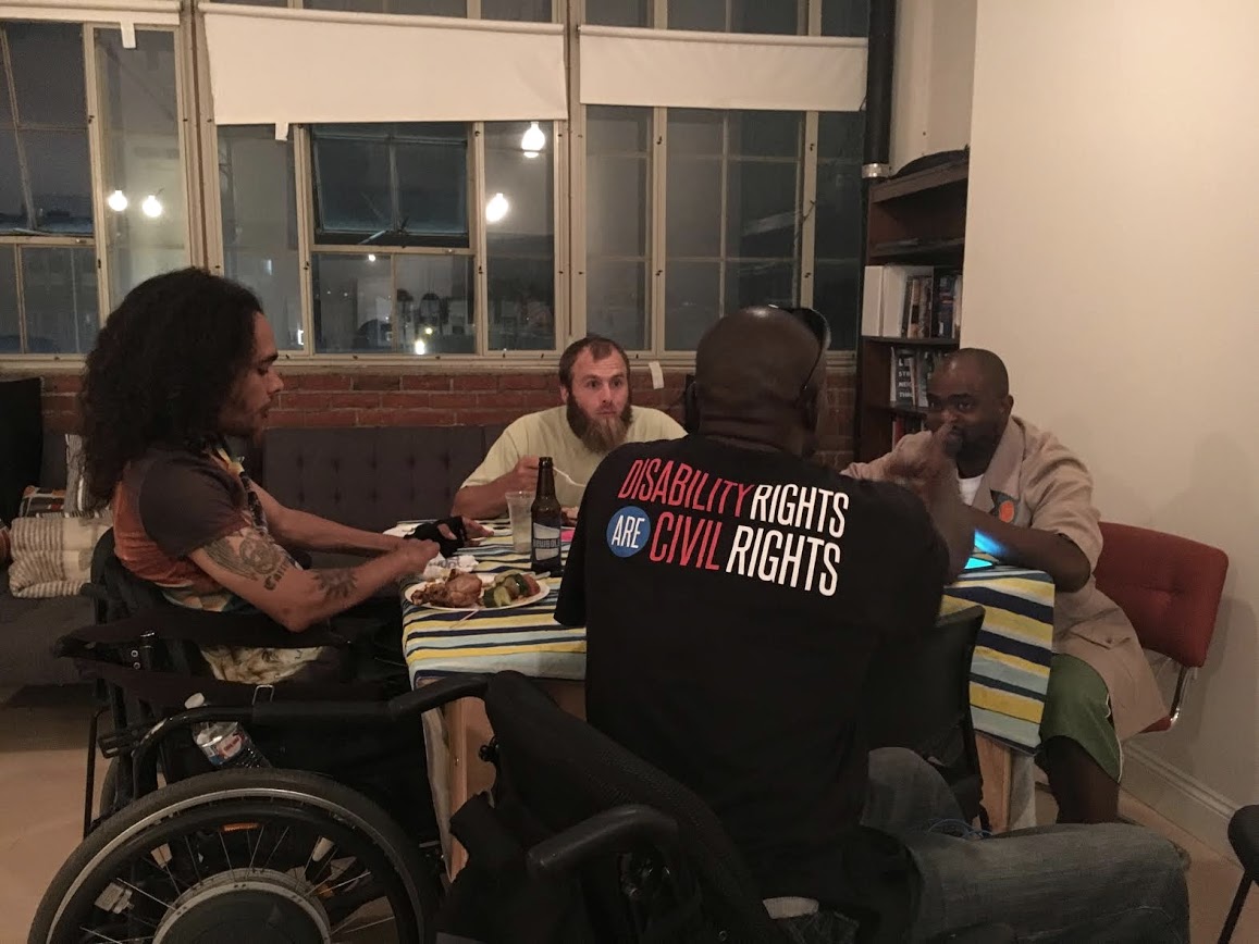 4 men sitting around a table,
	     having a meeting and discussion.